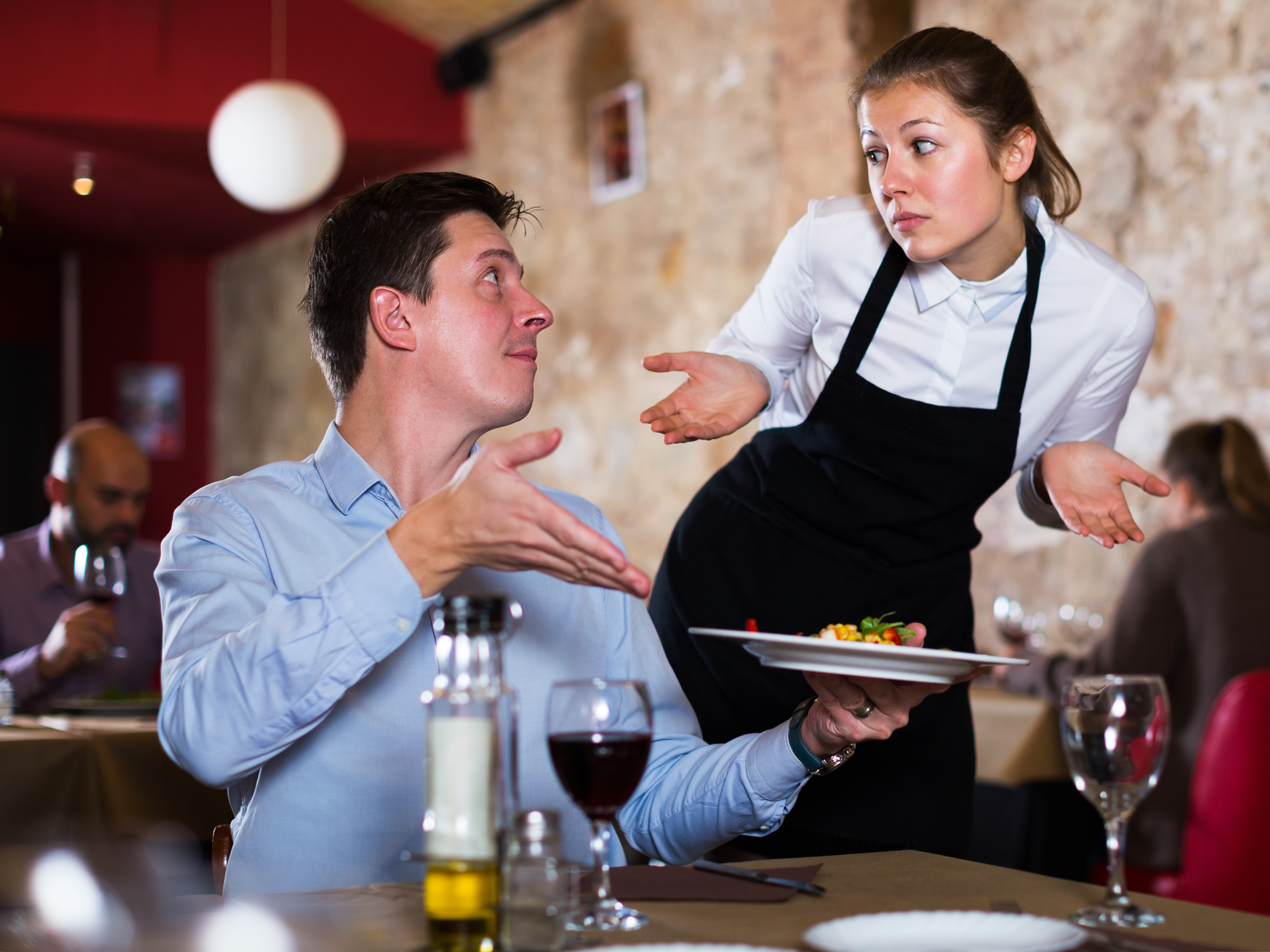 Gast im Restaurant beschwert sich bei Kellnerin über das Gericht auf dem Teller in seiner Hand