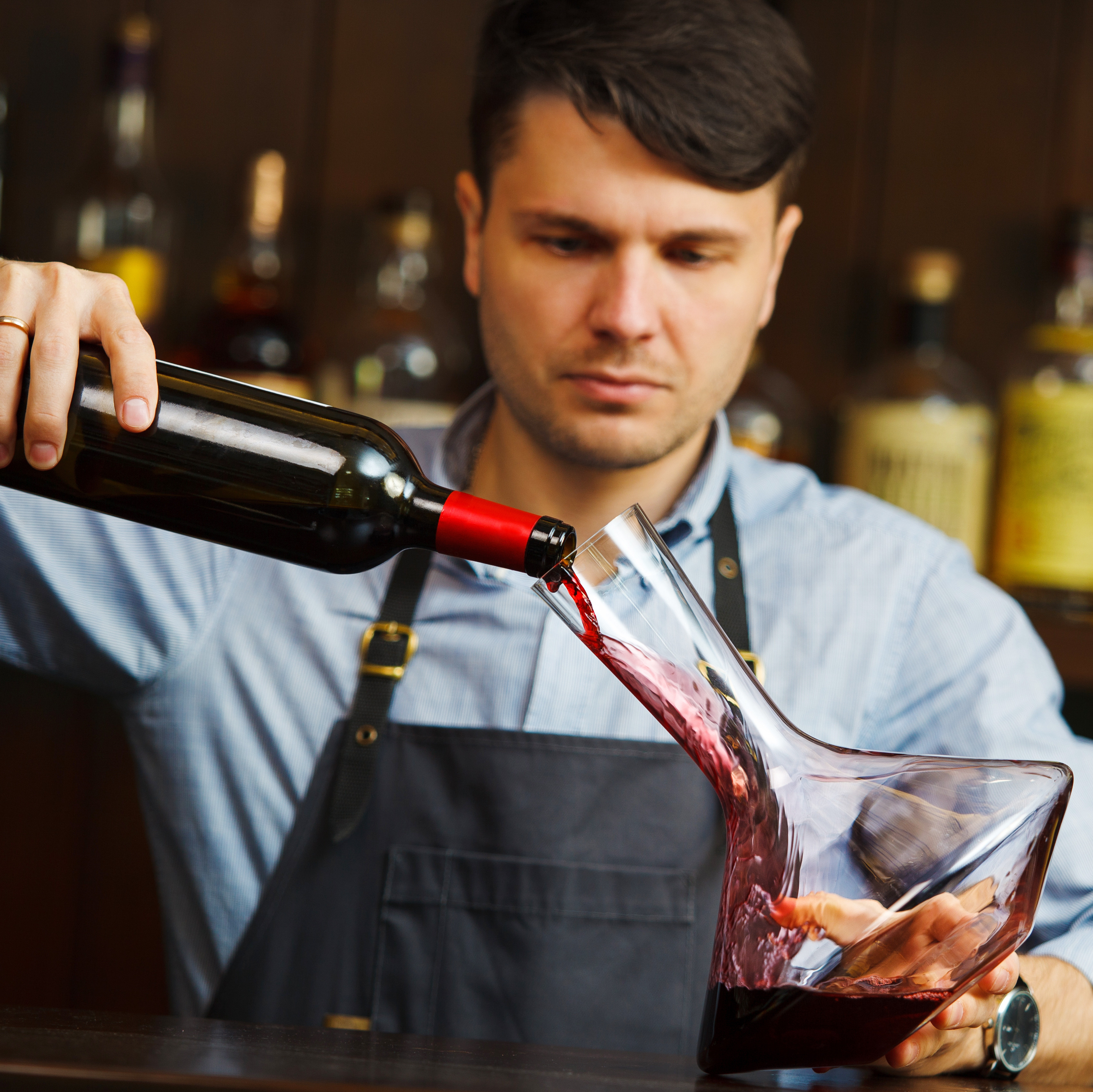 Mann gießt Rotwein in einen Dekanter