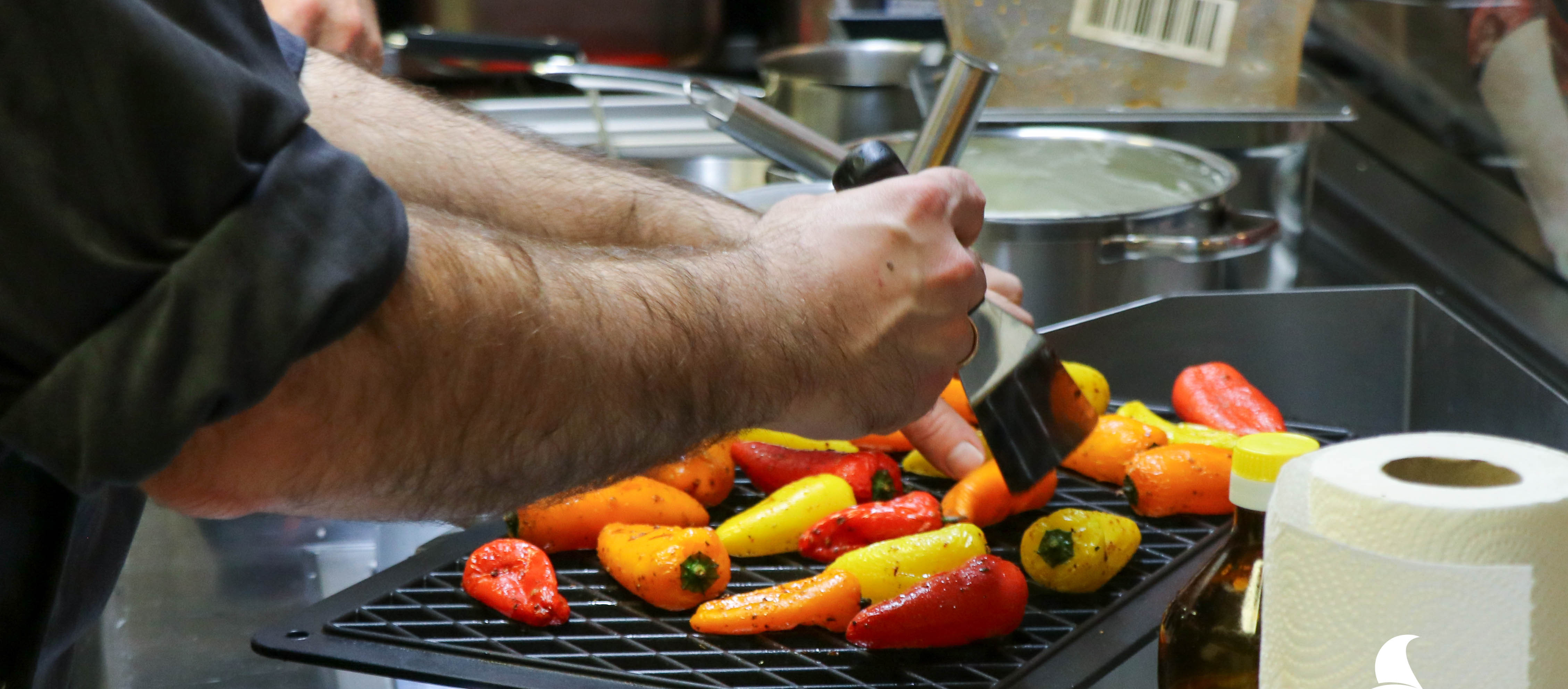 Koch wendet Mini Paprika auf einer Grillplatte