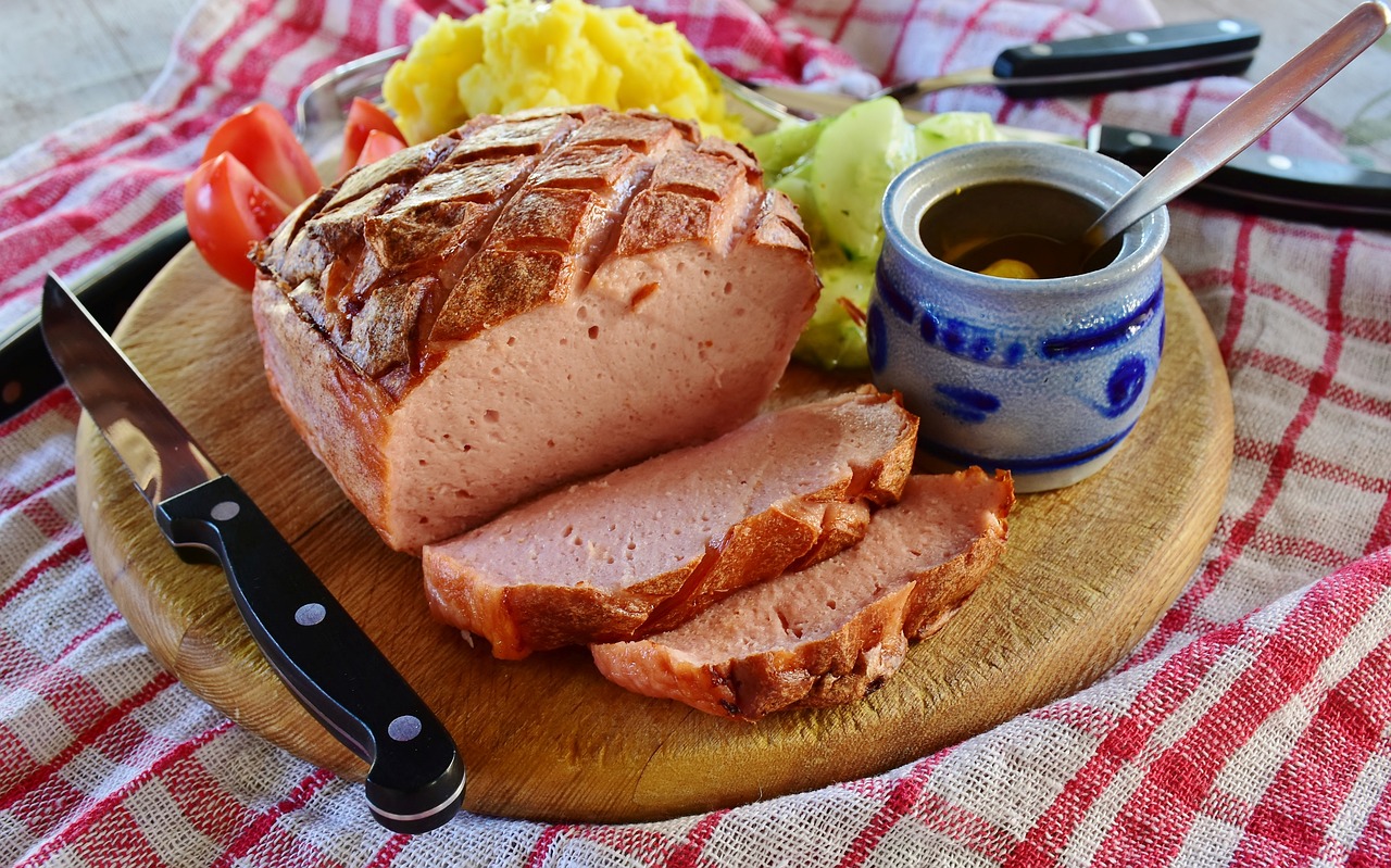 ein aufgeschnittener Leberkäse, angerichtet auf einem Brotzeit-Brett