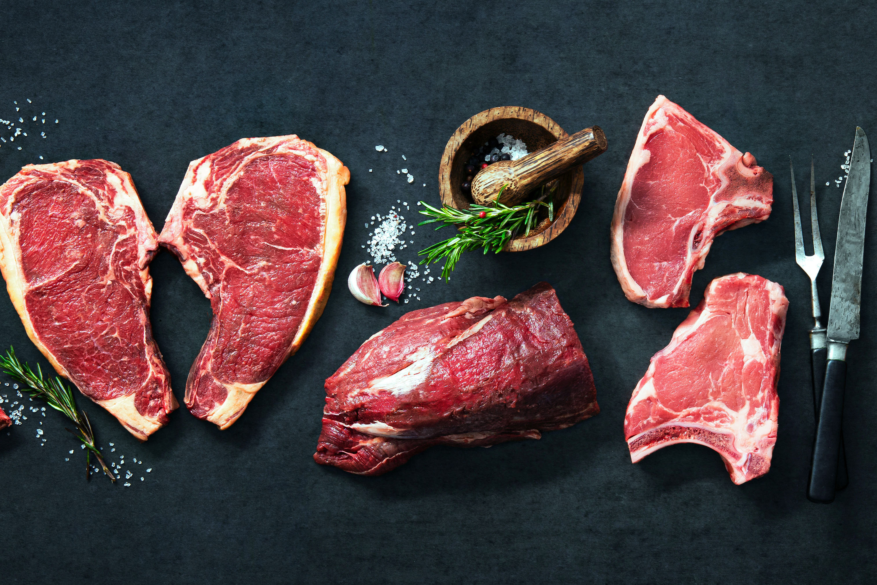 Fleisch mit Gewürzen und Messer auf einem Tisch 