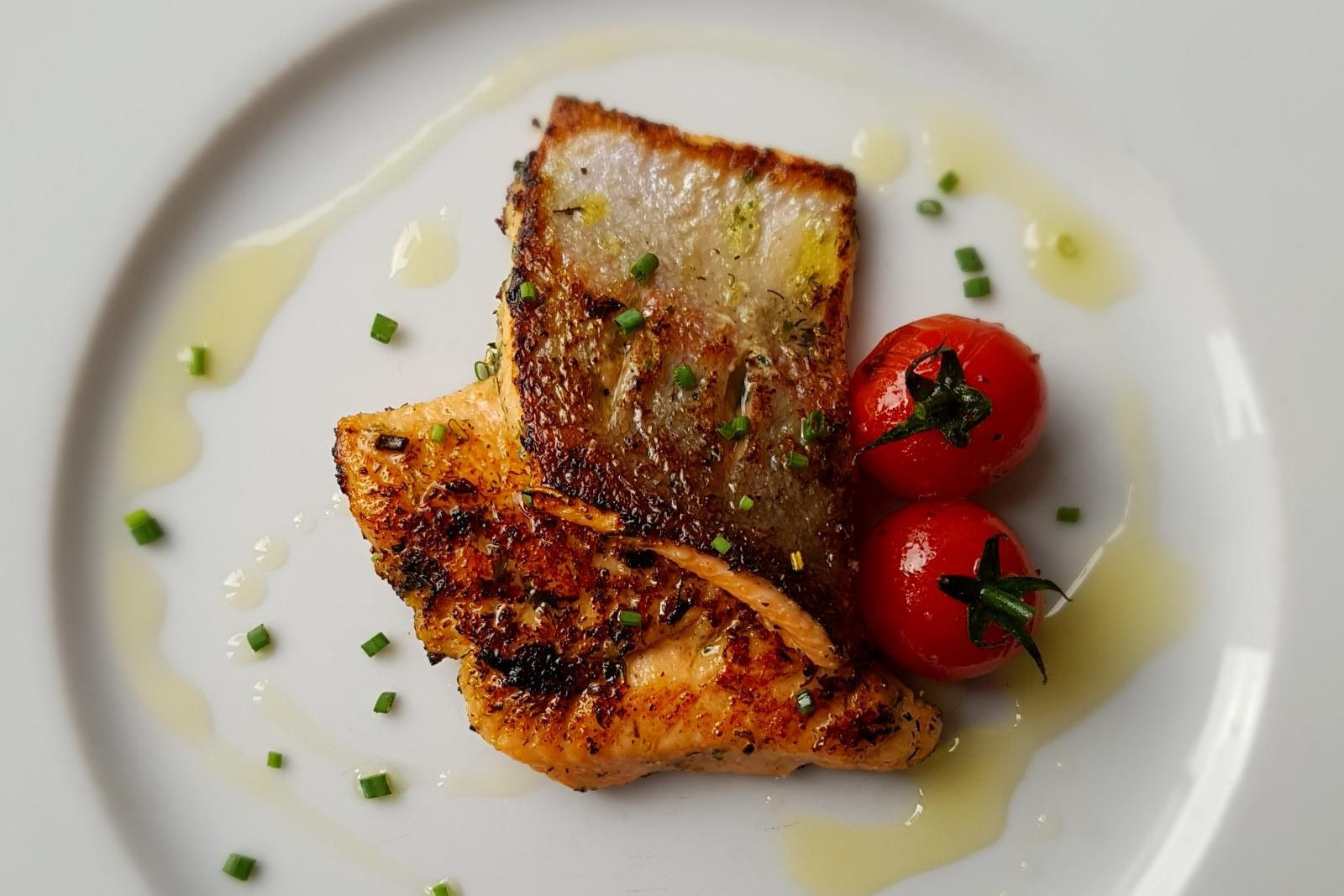 Gebratene Lachsforellenfilets mit Cherrytomaten auf einem Teller angerichtet