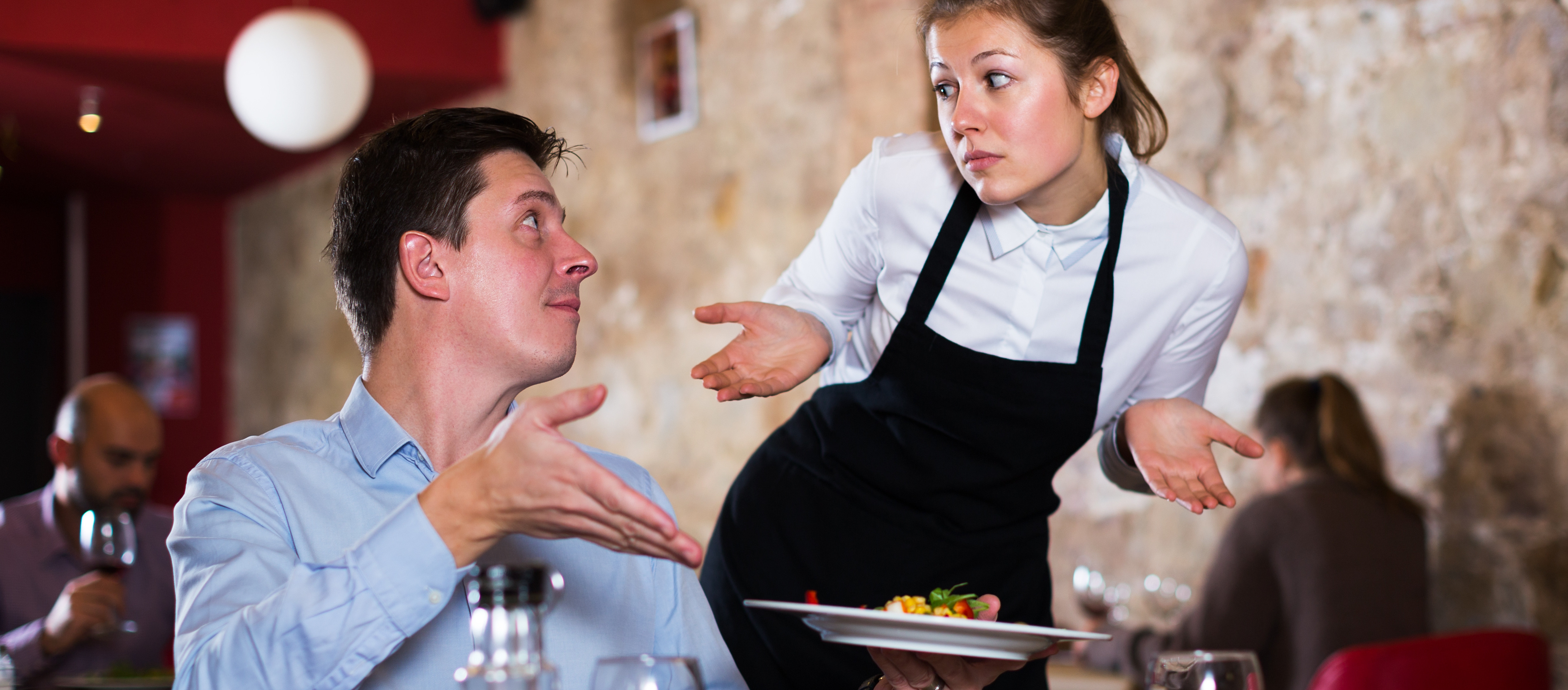 Gast im Restaurant beschwert sich bei Kellnerin über das Gericht auf dem Teller in seiner Hand